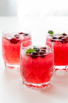 three glasses filled with red liquid and garnish