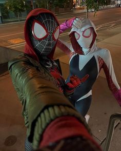 two people dressed as spider - man and deadpool standing next to each other on the street