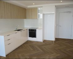 an empty kitchen with wood flooring and white cabinets