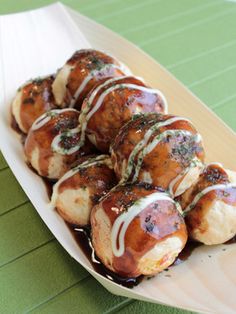 a white plate topped with meatballs covered in sauce and green toppings on top of a wooden table