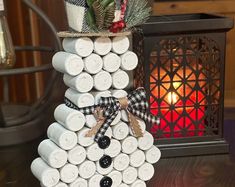 a snowman made out of wine corks on a table next to a lit candle