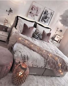 a bedroom with a large bed covered in blankets and pillows, lights on the headboard