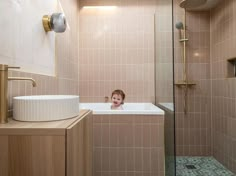 a child's face is peeking out from behind the bathtub in this bathroom