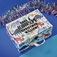 a personalised christmas gift box with dinosaurs on it and streamers in the background