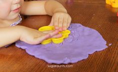 a young child playing with play dough on a table