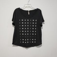 a black t - shirt with the words imagine on it hanging from a hanger