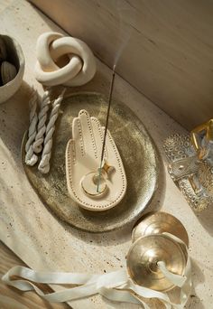 a table topped with gold and white items on top of a wooden table covered in ribbons