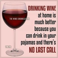 a glass of wine sitting next to a sign that says drinking wine at home is much better because you can drink in your pajamas and there's no last call