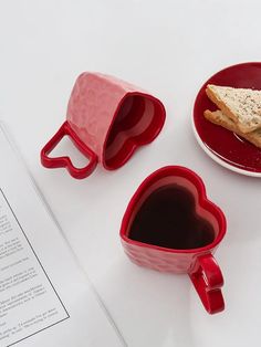 two heart shaped mugs next to a sandwich on a plate