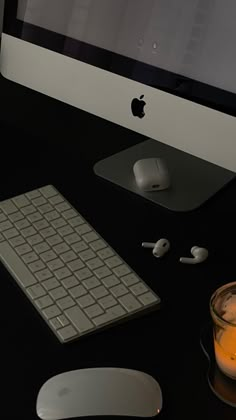 an apple computer sitting on top of a desk next to a glass of orange juice