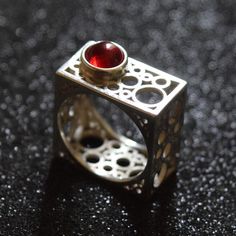 Discover the epitome of modern elegance with this handcrafted square silver ring, featuring a rich garnet centerpiece. The unique geometric design of this piece draws inspiration from contemporary architecture, offering a bold statement while maintaining a minimalist aesthetic. Each ring is meticulously crafted to highlight the natural beauty of the garnet, making it a perfect gift for those born in January or anyone who appreciates artisan jewelry. Add a touch of sophistication to any outfit with this distinctive ring. Modern Red Rings For Formal Occasions, Modern Red Ring For Formal Occasions, Modern Square Rings For Formal Occasions, Modern Sterling Silver Jewelry With Square Cut, Modern Sterling Silver Rings With Rectangular Stone, Modern Garnet Jewelry For Anniversary, Modern Ruby Jewelry As A Gift, Modern Red Ruby Ring For Formal Occasions, Modern Ruby Ring For Formal Occasions