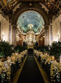 the interior of a church decorated with flowers and greenery on either side of the aisle