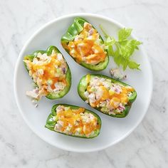 four stuffed peppers on a white plate with lettuce garnish and cheese