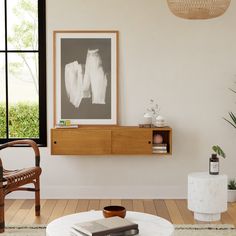 a living room filled with furniture and a painting hanging on the wall above a coffee table