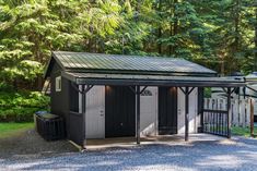 a small black shed sitting in the middle of a forest