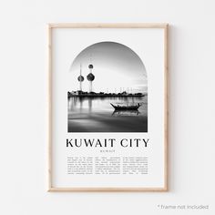 a black and white photo hanging on a wall next to a wooden frame with the words kuwait city in it