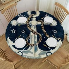 the table is set with white plates and silverware, along with an anchor - themed placemat