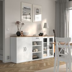 a dining room with white furniture and pictures on the wall