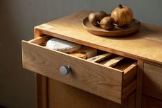 a wooden table with some fruit on it and a plate in the drawer next to it