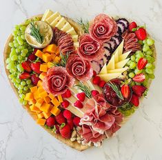 a heart shaped platter filled with meats, cheeses and fruit