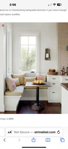 an image of a small kitchen with white cabinets and wood flooring, as well as a window seat