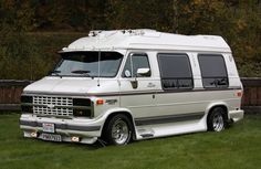 an old white van parked in the grass