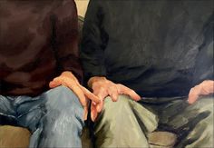 two people sitting on a couch with their hands together