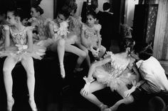 several young ballerinas in tutus and leotards sitting on a bench