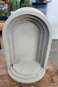 three cement dishes sitting on top of a wooden table next to potted planters