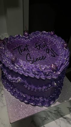 a purple cake with writing on it sitting on top of a table