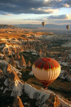 three hot air balloons flying over rocky terrain