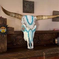 a cow skull with beaded necklaces on it's head sitting on a mantle