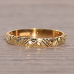 a gold wedding ring sitting on top of a wooden table