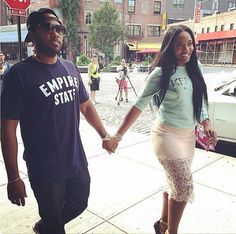 a man and woman holding hands while walking down the street