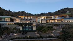 this is an image of a modern house in the mountains at night with lights on