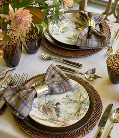 a table set with place settings and flowers in vases