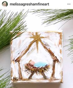 a christmas ornament with a nativity scene hanging from the top of a pine tree