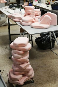 several pink chairs stacked on top of each other in front of a table with black bags