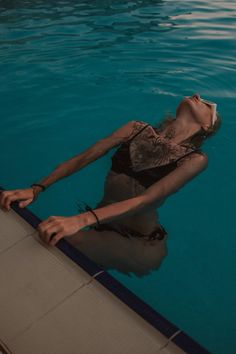 a woman is floating in the pool with her head above the water's edge