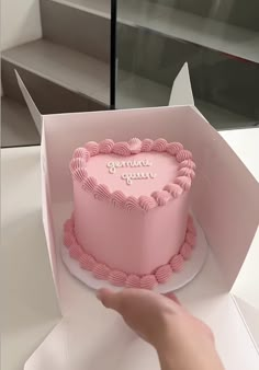 a pink heart shaped cake sitting inside of a box on top of a white counter