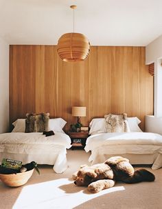 two beds in a room with wood paneling and pillows on the floor next to each other