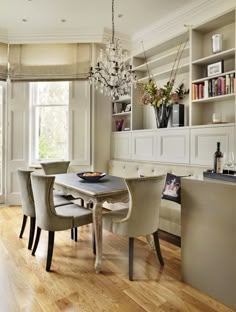 a dining room table with chairs and a chandelier hanging from it's ceiling