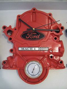 a red clock mounted to the side of a white wall with ford logo on it