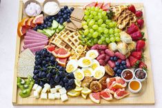 a wooden platter filled with assorted fruits and waffles on top of a table