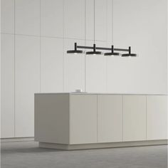 an empty white counter with three lights hanging from it's sides and two sinks below