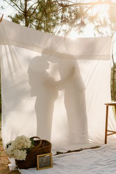 two people are kissing in front of a white canopy with flowers on the bed and an empty basket next to it