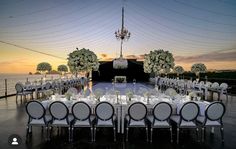 an outdoor dining area with tables and chairs set up for a formal function at sunset