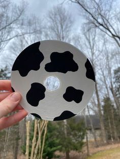 a hand holding up a black and white cow print disc