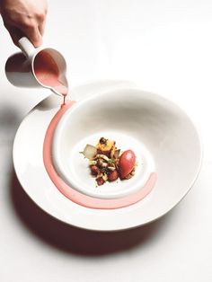 a person pouring sauce into a white bowl