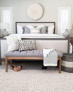 a bed with pillows and blankets on top of it in a bedroom next to two baskets